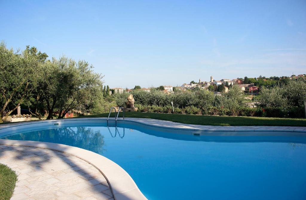 a large blue swimming pool with trees in the background at Agriturismo Carnaroli in Piagge