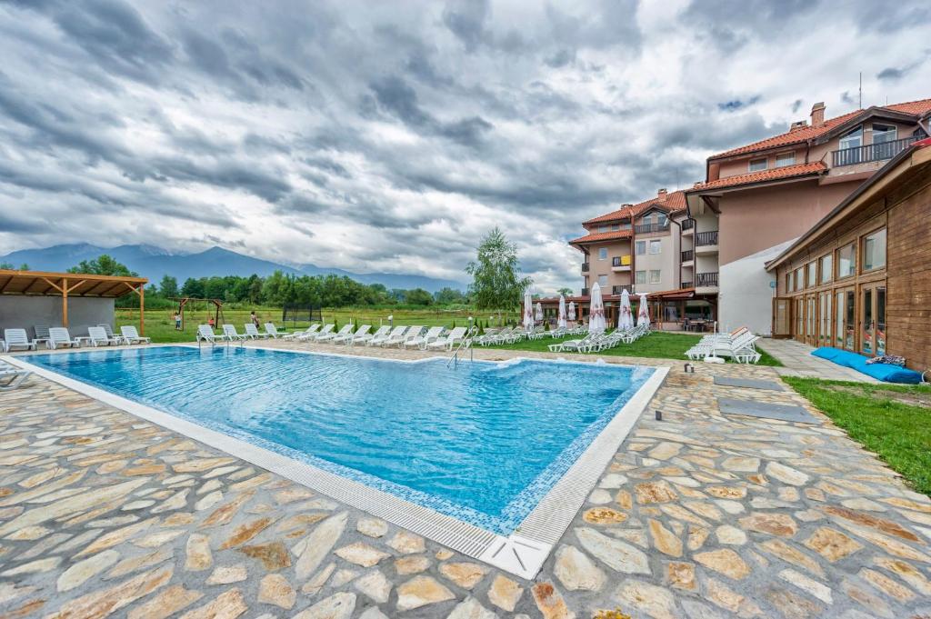 a swimming pool with chairs and a building at Thermal Hotel Seven Seasons in Bansko