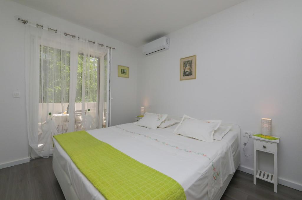 a white bedroom with a large bed and a window at Apartment M&J Supetar in Supetar