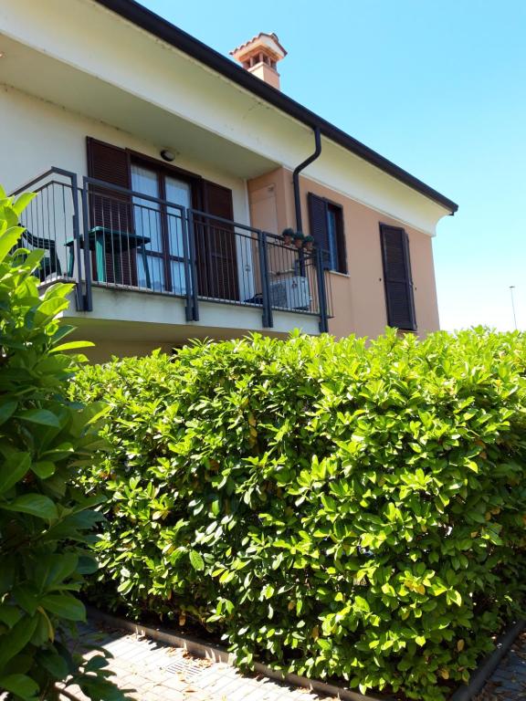 a hedge in front of a house with a balcony at La Cornice del Garda in Cavalcaselle