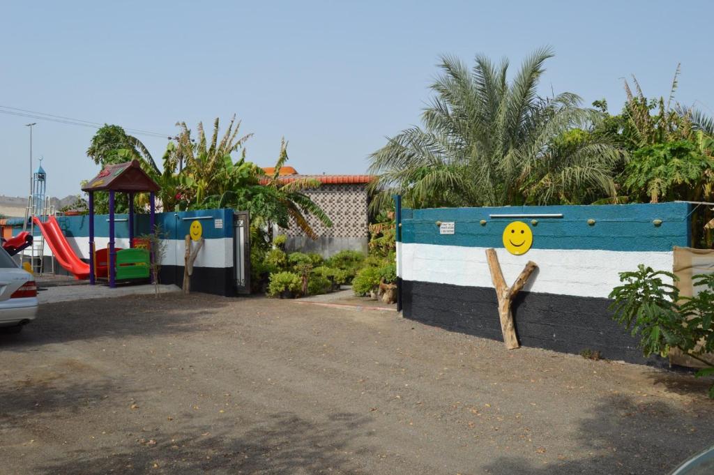 einen Spielplatz mit einer blauen und weißen Wand neben einem Spielplatz in der Unterkunft Happiness Farm in Hatta
