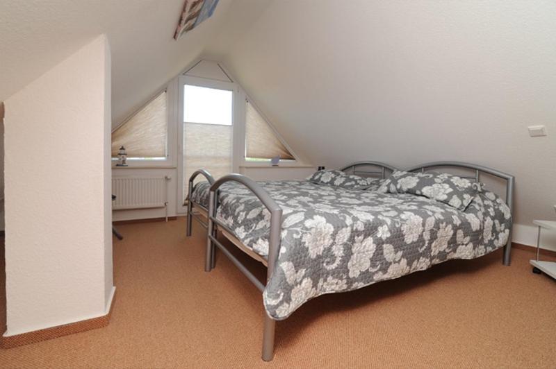 a bedroom with a bed and a window at Nordseesonne Greetsiel in Krummhörn