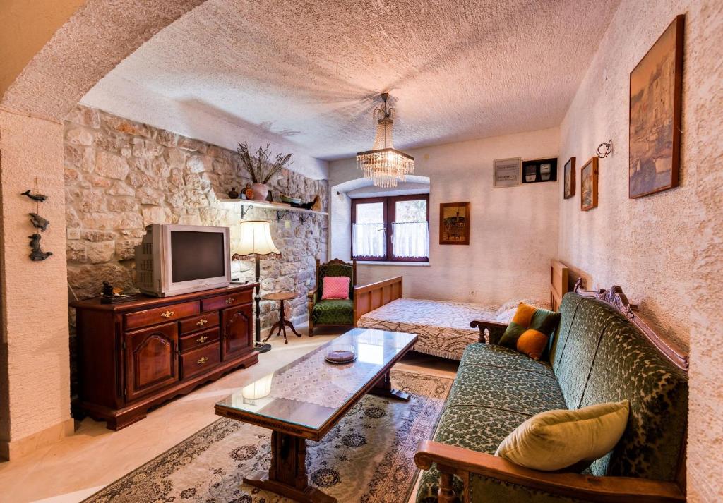 ein Wohnzimmer mit einem Sofa und einem TV in der Unterkunft Apartments Land - 100m to the sea in Zlarin