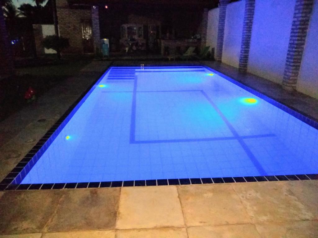 une grande piscine avec des lumières bleues. dans l'établissement casa na praia de guajiru, à Guajiru