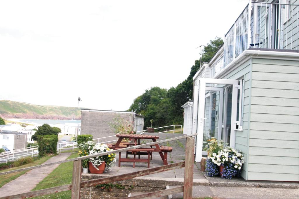 a porch with a picnic table on the side of a building at Freshwater Bay Holiday Cottages in Pembroke
