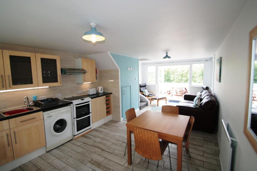 a kitchen and a living room with a table at Freshwater Bay Holiday Cottages in Pembroke