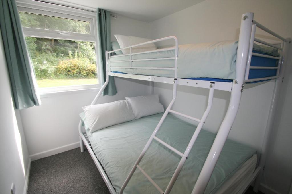 a bunk bed in a small room with a window at Freshwater Bay Holiday Cottages in Pembroke