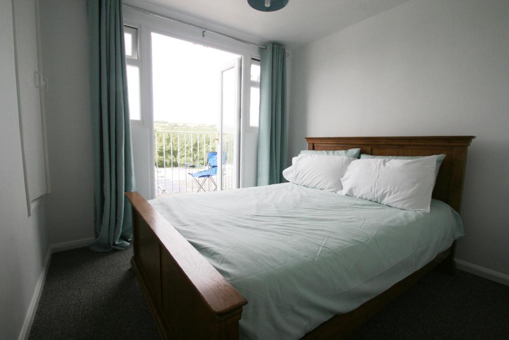 a bedroom with a bed with a large window at Freshwater Bay Holiday Cottages in Pembroke