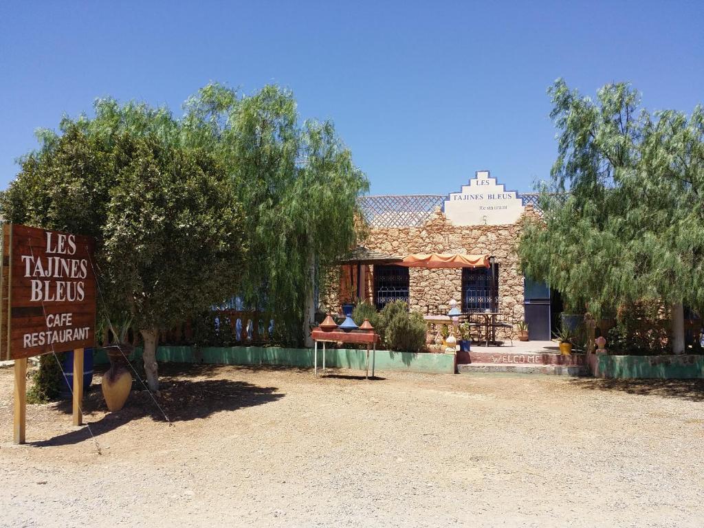 una señal frente a un edificio con un árbol en Les Tajines Bleus en Tamanar