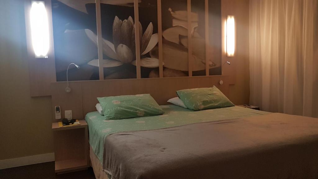 una camera con un letto con due cuscini verdi di Flat Manaus a Manaus