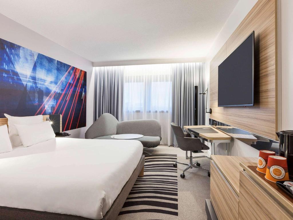 Cette chambre comprend un lit, un bureau et une télévision. dans l'établissement Novotel Tours Centre Gare, à Tours