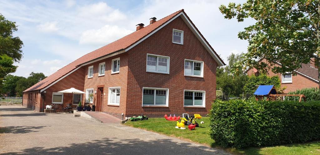 a red brick house with a garden in front of it at Ferienwohnung Landliebe in Leer