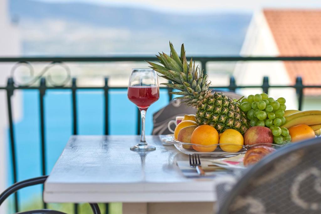 a plate of fruit on a table with a glass of wine at Apartment Ugrina in Trogir
