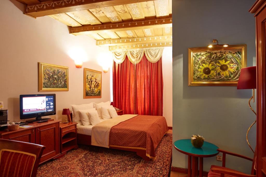 een slaapkamer met een bed en een televisie en een tafel bij Royal Ricc in Brno