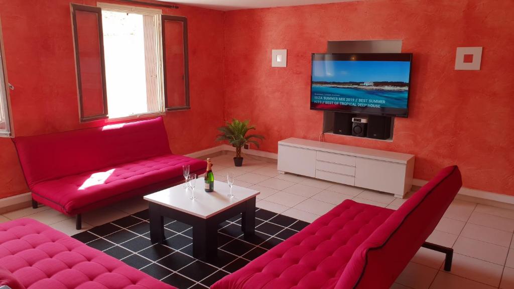 een woonkamer met rode meubels en een flatscreen-tv bij Les Barons de Guers in Castelnau-de-Guers