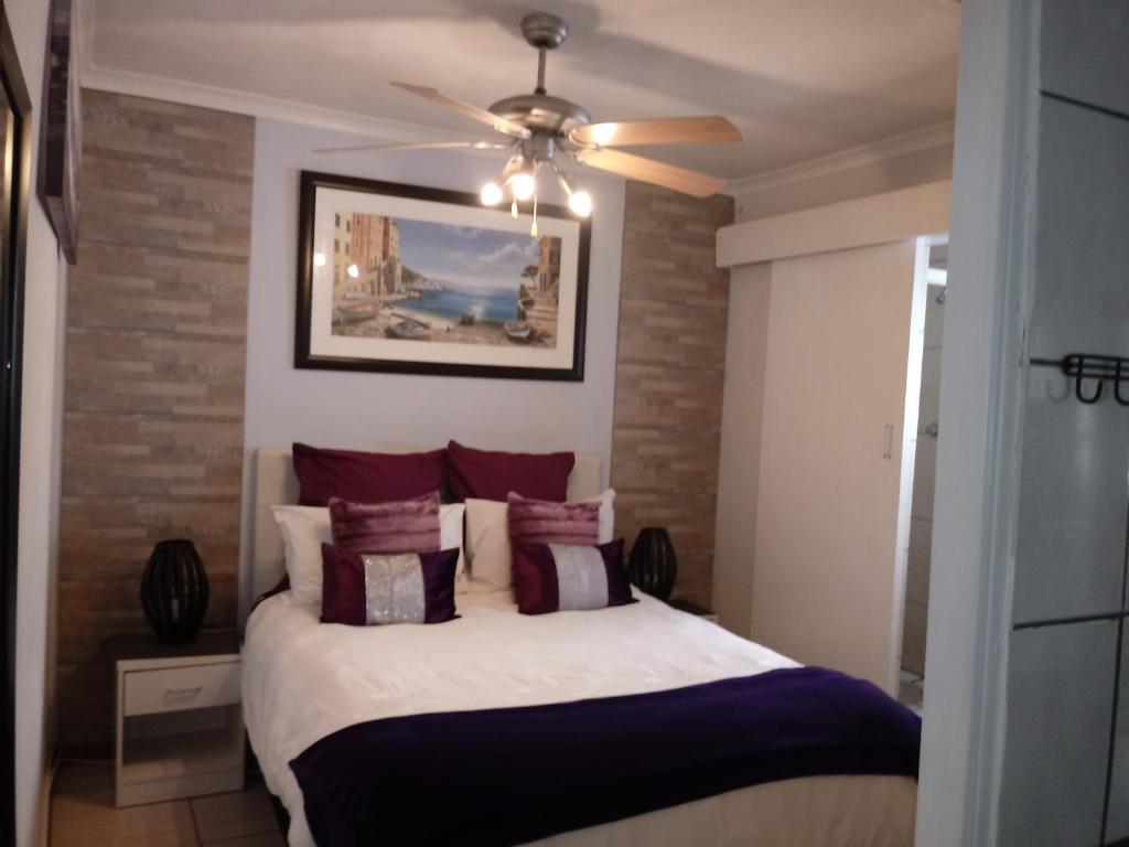 a bedroom with a bed with a ceiling fan at Villa Armaan in Brackenfell