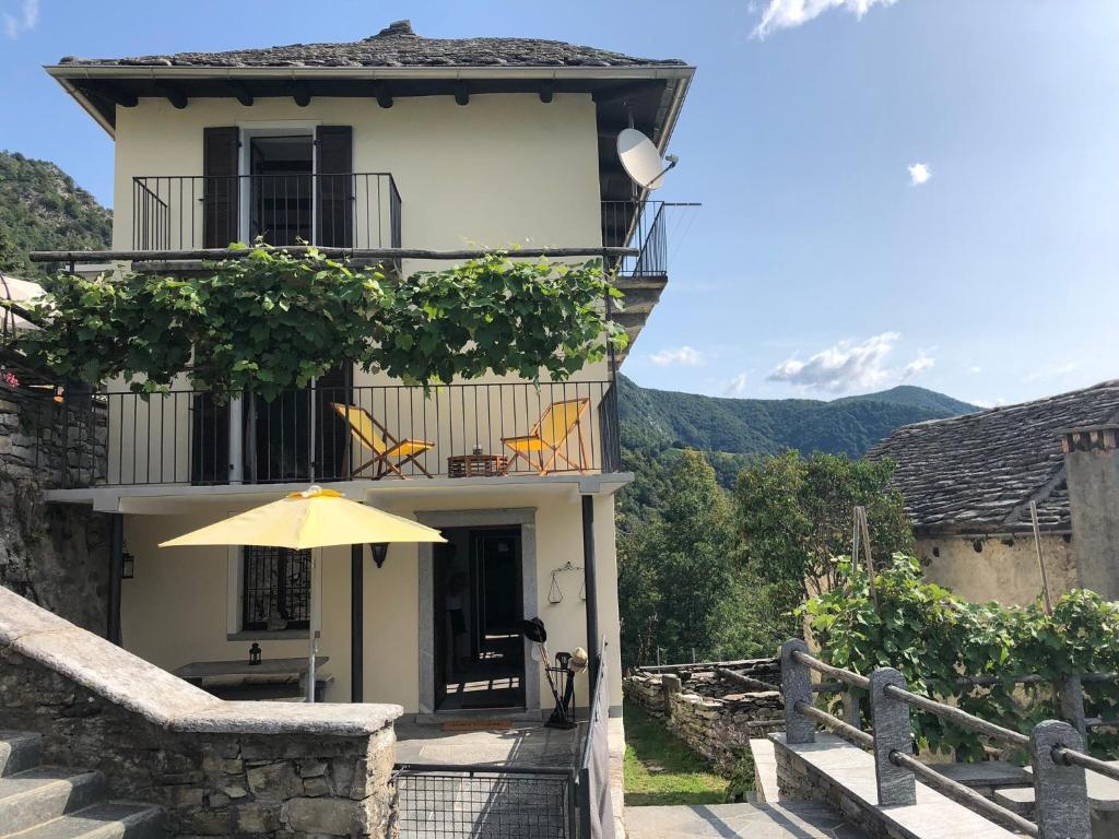 Borgnone的住宿－Casa Ruscada，一座带黄色遮阳伞和阳台的建筑