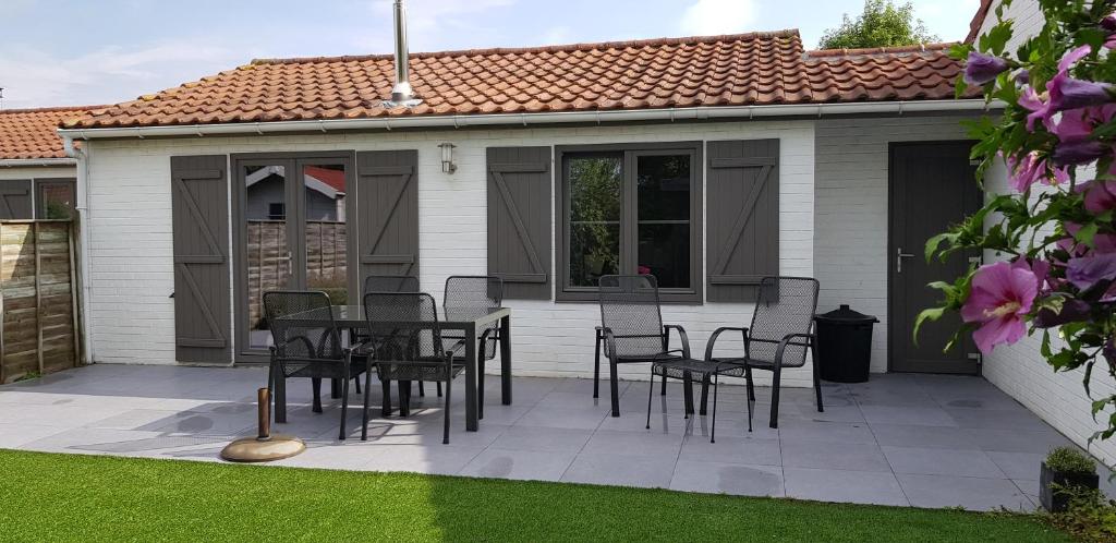 eine Terrasse mit schwarzen Stühlen und einem Tisch vor einem Haus in der Unterkunft Duinenhuis Zeepolder 27 in De Haan