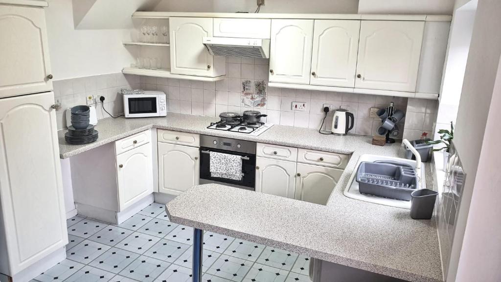 a kitchen with white cabinets and a stove top oven at Anvil Drive - Birmingham BnBs in Oldbury