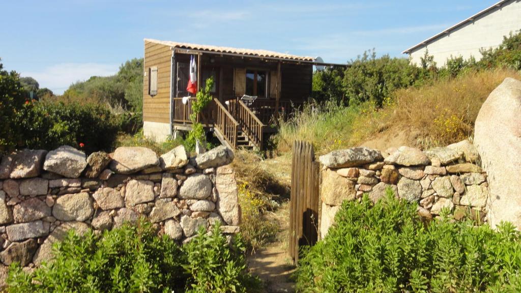 a tiny house on a hill with a stone wall at U Roccu in Coti-Chiavari