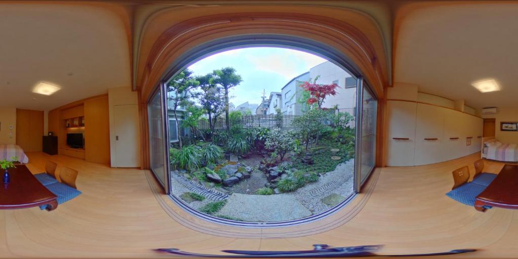 ein großes rundes Fenster in einem Zimmer mit Garten in der Unterkunft Shinjuku Garden House in Tokio