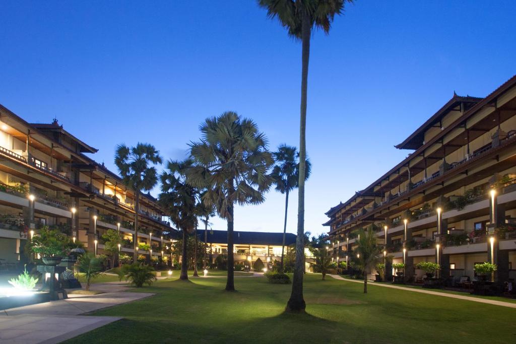 a courtyard with palm trees in front of a building at Peninsula Beach Resort in Nusa Dua