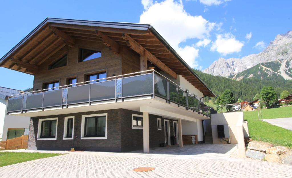a house with a balcony with mountains in the background at Haus Intaba in Ramsau am Dachstein