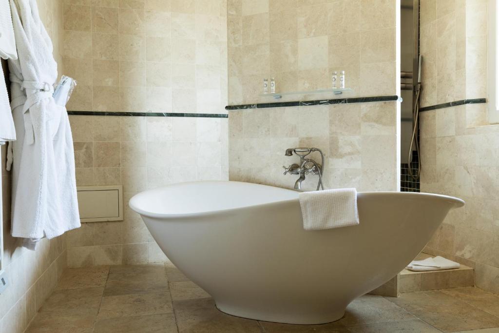 a bathroom with a white bath tub in a room at Hôtel Mas Valentine in Saint-Rémy-de-Provence