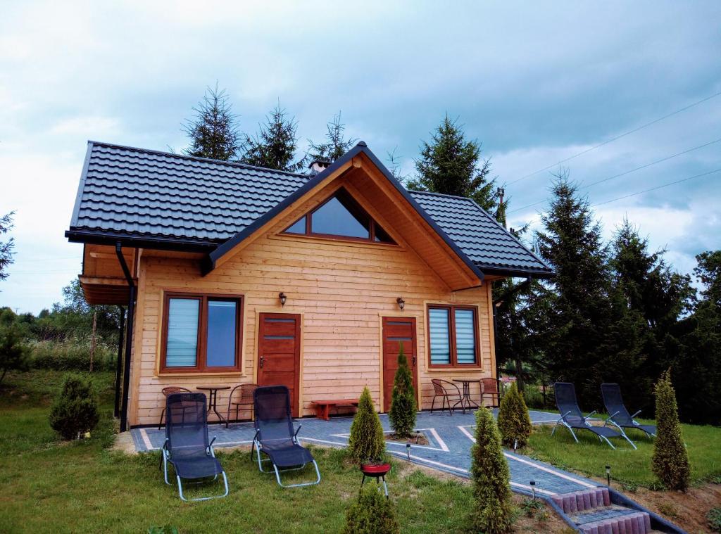 una pequeña casa de madera con sillas en el patio en Chrząszczewo Widokowe Wzgórze, en Uherce Mineralne