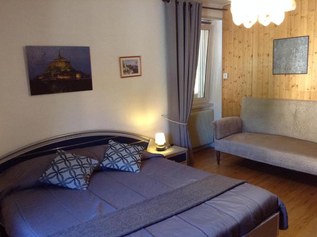 una camera con letto, divano e sedia di Chez Michel a Le Bonhomme