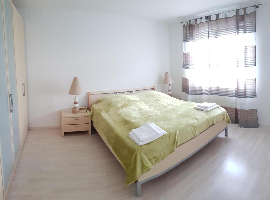 a white bedroom with a bed and a window at Ferienwohnung Waldvogel in Immenstaad am Bodensee