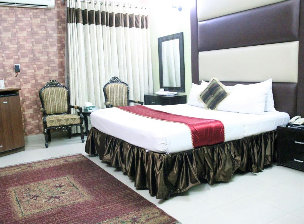 a bedroom with a bed, chair, table and lamp at Tourist Inn Hotel in Lahore