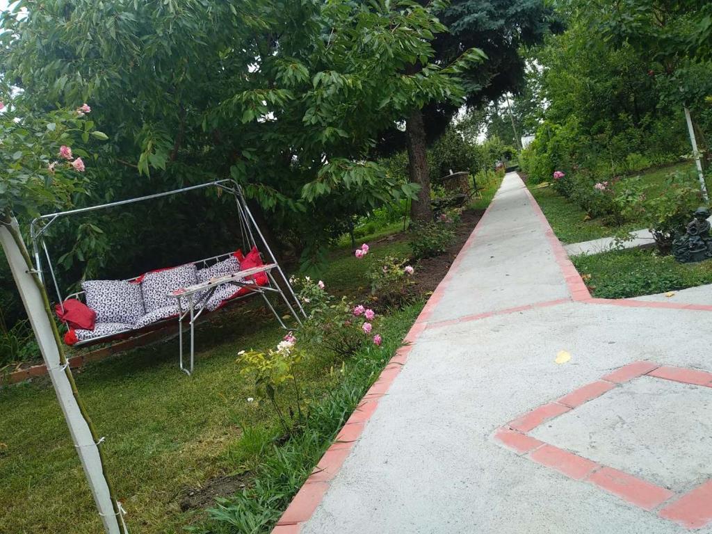a bench sitting on the grass next to a sidewalk at Apartment Ljupka in Pančevo