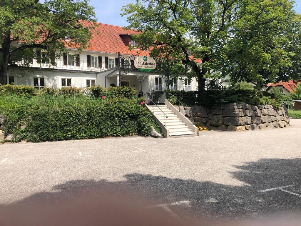 a white building with a stone wall and stairs at Ennstalerhof in Grossraming