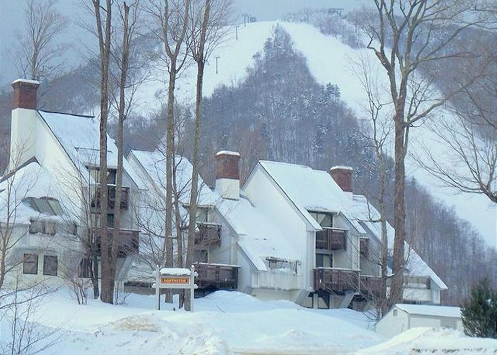 una gran casa blanca con nieve en el techo en Ski In/Out Trailside Townhome en Killington