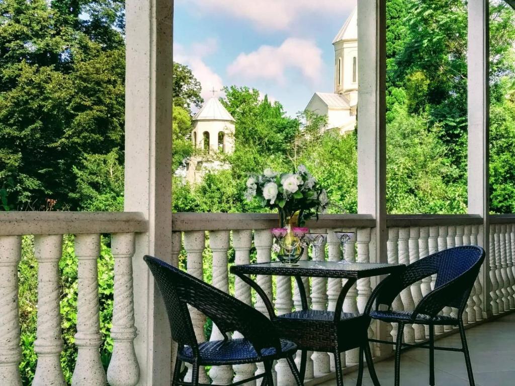 a table and chairs on a balcony with a view of a castle at Guest House Ukimerioni in Kutaisi