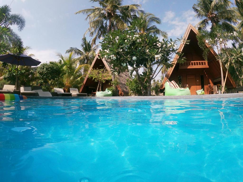 a large swimming pool in front of a resort at Lucy's Garden Hotel in Gili Air