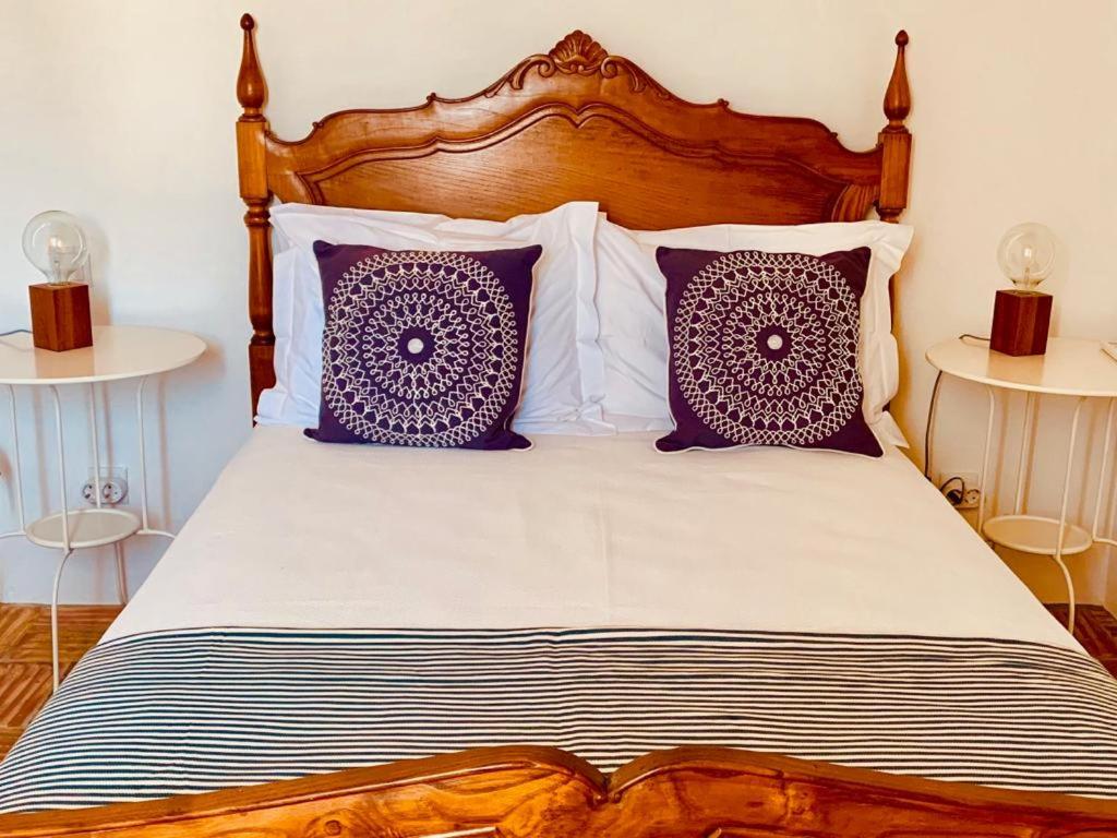 a bed with purple and white pillows on it at Casas de Mértola - N. Sª das Neves in Mértola