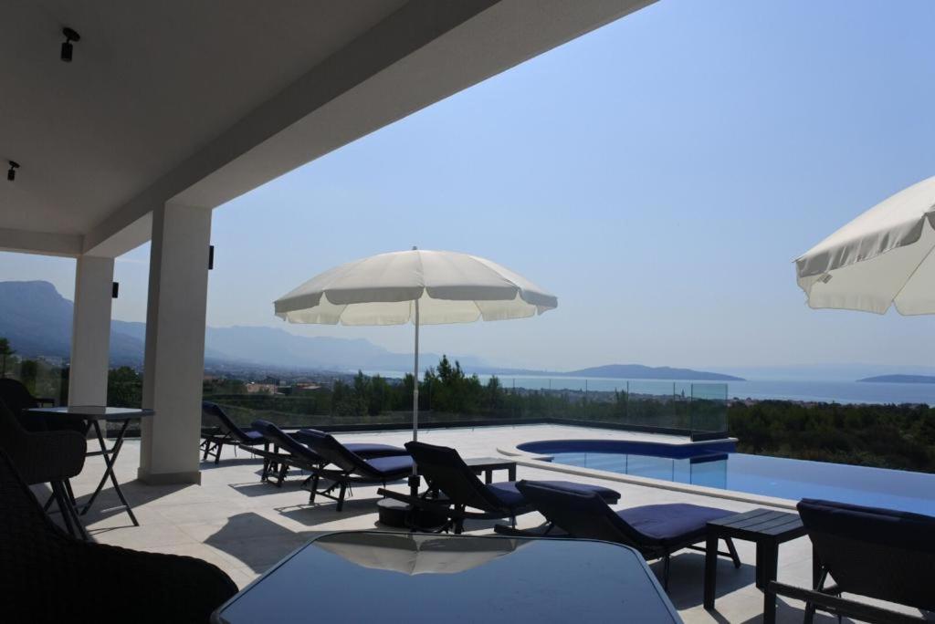 a patio with chairs and an umbrella and a swimming pool at Villa Orao in Kastel Novi