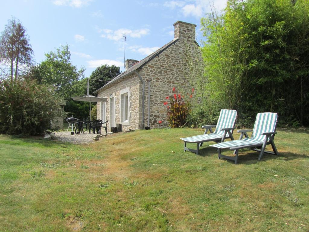 2 chaises assises devant une maison en pierre dans l'établissement Gite Sant Venter, à Plounevez-Quintin
