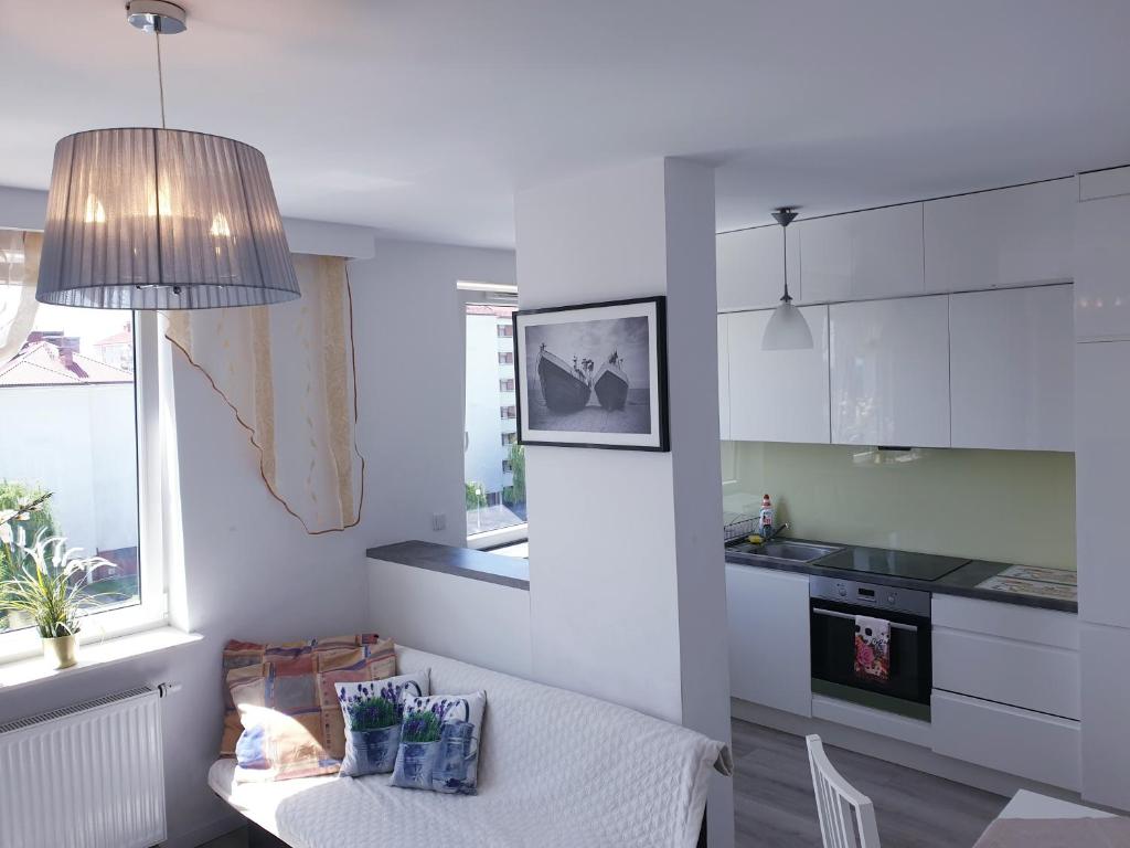 une cuisine avec des placards blancs, une table et une fenêtre dans l'établissement Apartamenty Promenada, à Varsovie