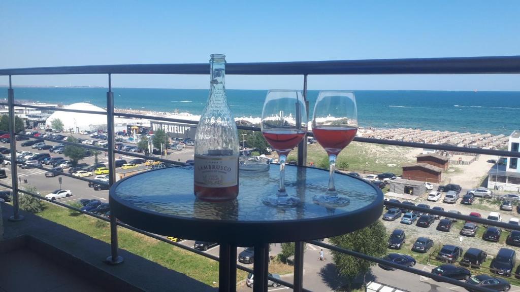 2 bicchieri di vino seduti su un tavolo sul balcone di Summerland Nikos Residence a Mamaia
