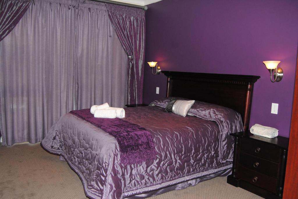 ein lila Schlafzimmer mit einem Bett mit zwei Handtüchern darauf in der Unterkunft Villa D este in Kimberley