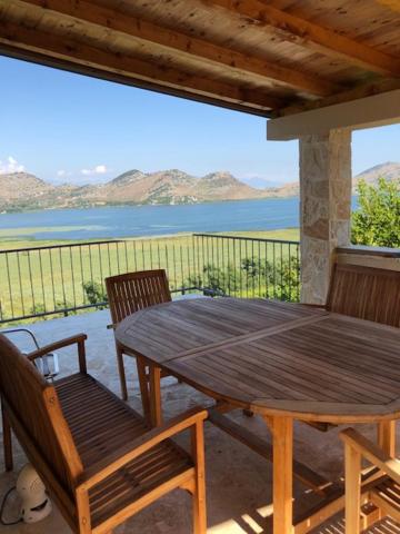 una mesa de madera y sillas con vistas al agua en Skadar lake house Bobija, en Podgorica