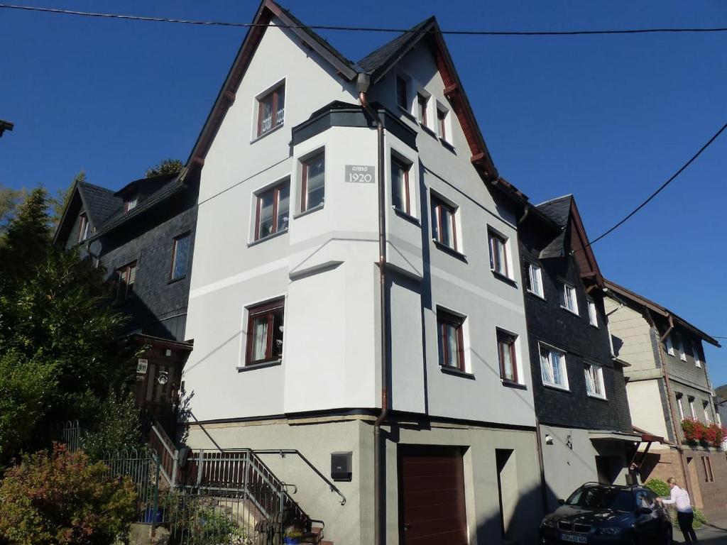 a white building with a black roof at Ferienwohnung Schelhorn in Mengersgereuth-Hämmern