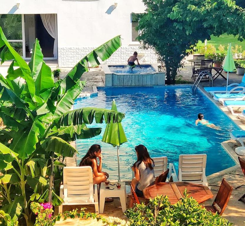 two women sitting under an umbrella in a swimming pool at Parla Apart Hotel in Cesme