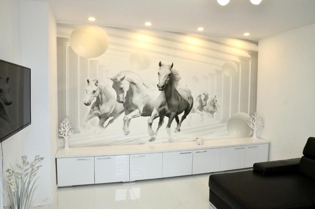 a wall mural of four horses running in a living room at Apartament Domi in Gniezno