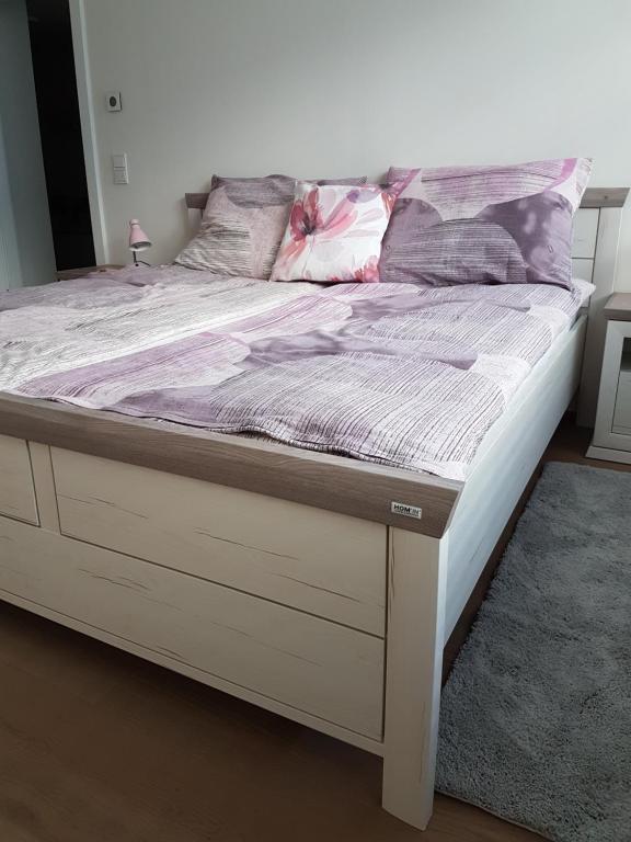 un letto con struttura in legno e un letto bianco con mattressvisor di Vienna Home48 a Vienna