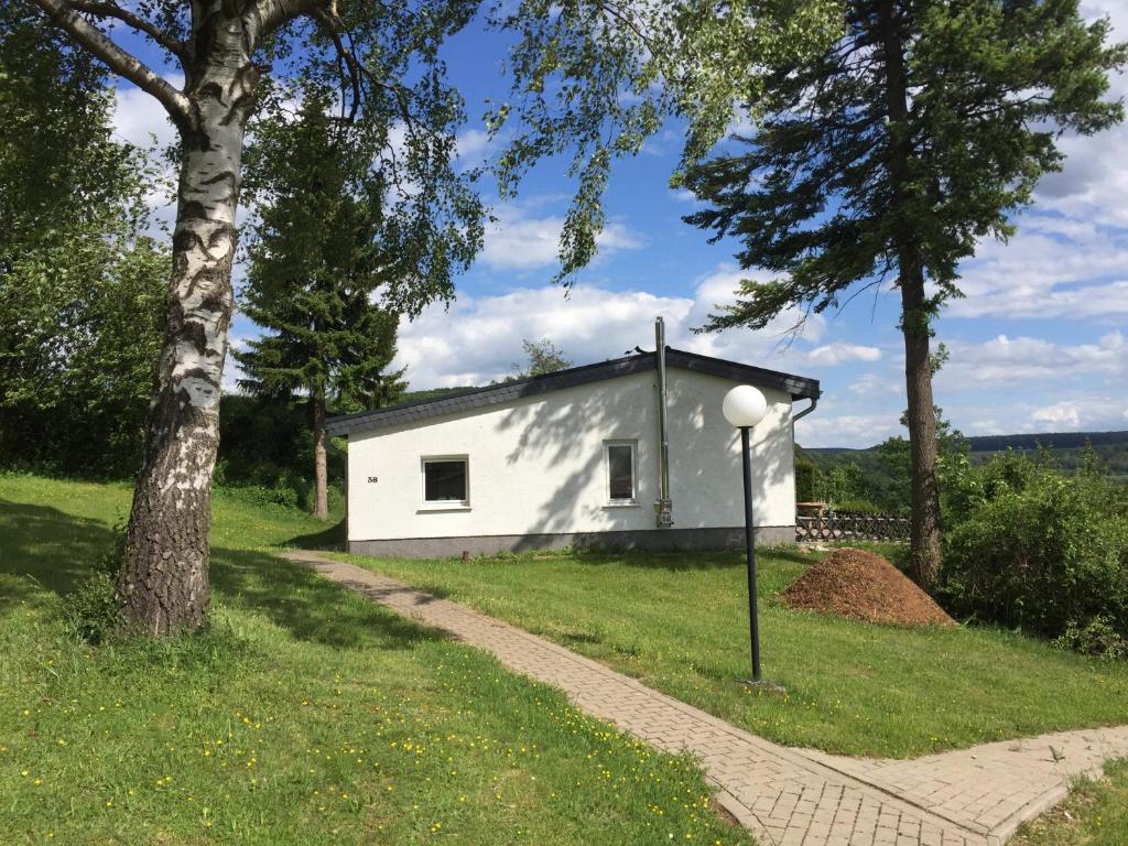 a small white house in a field with trees at Europa-Feriendorf Husen in Husen