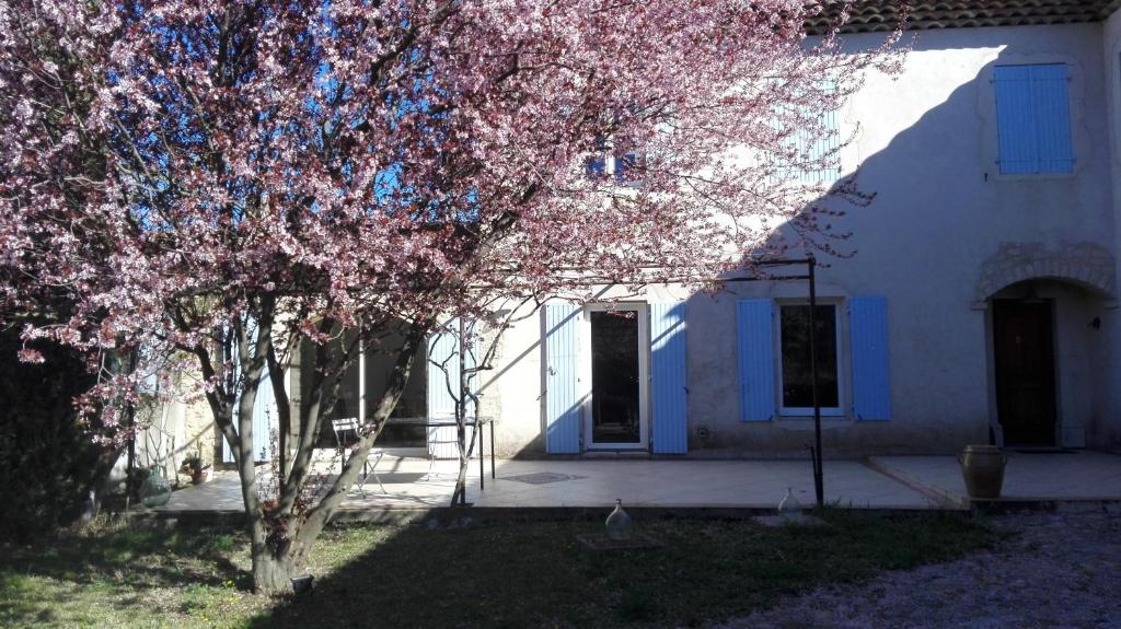 un árbol frente a una casa blanca con flores rosas en Mas Bohème, en Espeluche